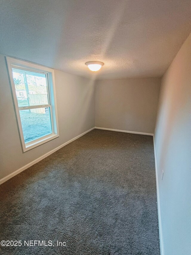 unfurnished room featuring a textured ceiling, carpet flooring, and baseboards