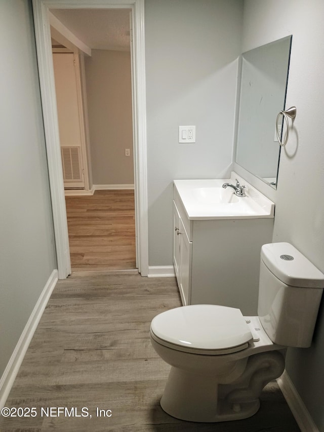 bathroom featuring toilet, visible vents, wood finished floors, and vanity