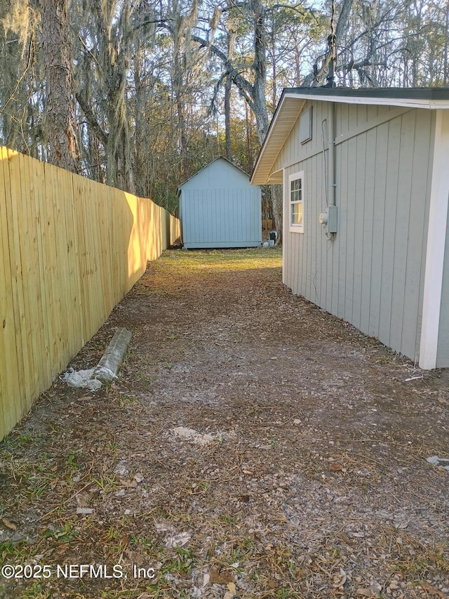 view of yard with a shed, fence, and an outdoor structure