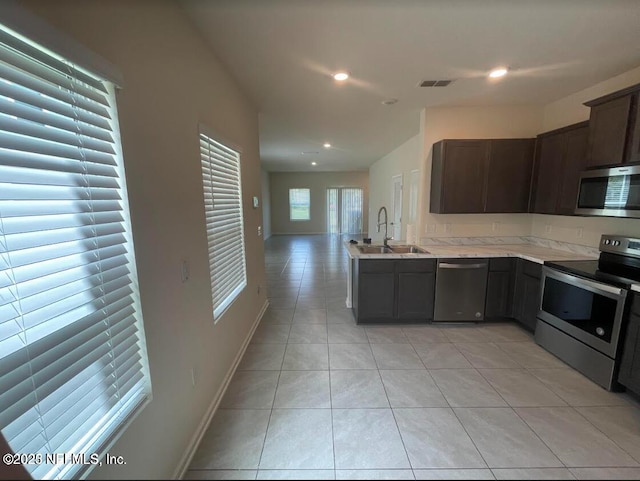 kitchen with light tile patterned flooring, appliances with stainless steel finishes, dark brown cabinetry, and sink