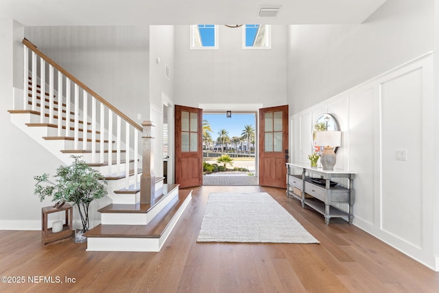 foyer entrance with wood-type flooring and a towering ceiling