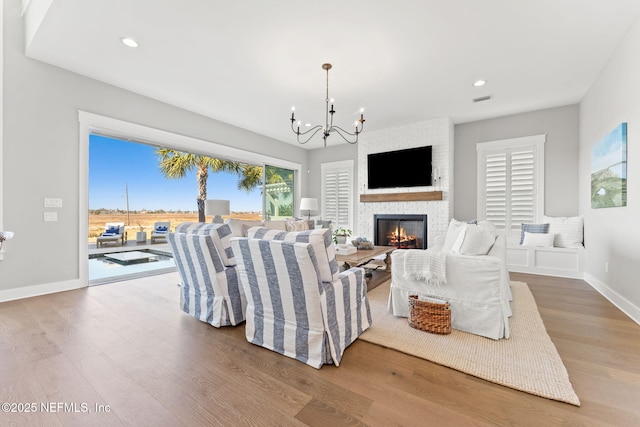 living room with a chandelier, hardwood / wood-style floors, and a fireplace