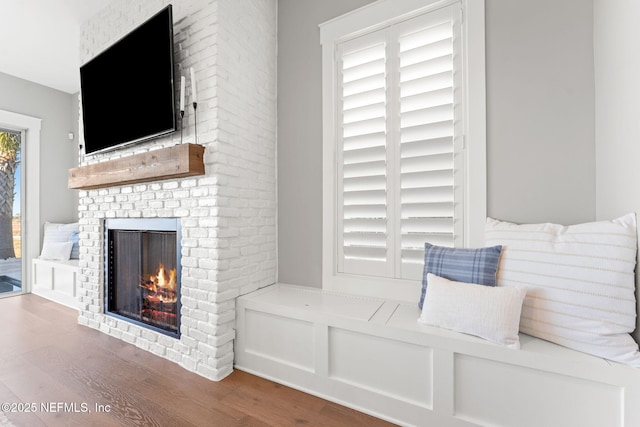 living room with a brick fireplace and wood-type flooring