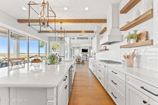 kitchen featuring light stone countertops, custom exhaust hood, a large island, and pendant lighting