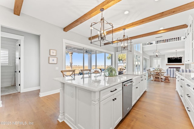 kitchen featuring decorative light fixtures, white cabinetry, a kitchen island with sink, a notable chandelier, and beamed ceiling