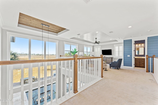 corridor with wooden ceiling, a raised ceiling, crown molding, and light carpet