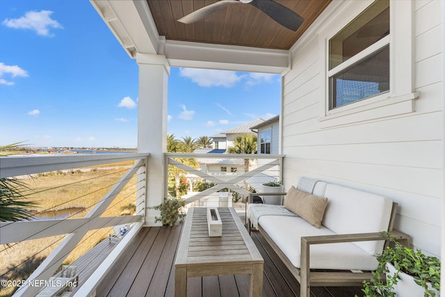 balcony with an outdoor living space, ceiling fan, and a water view