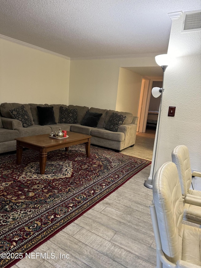 living room with ornamental molding, a textured ceiling, and light hardwood / wood-style flooring