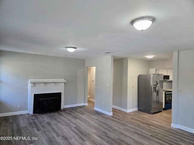 unfurnished living room with a brick fireplace and light hardwood / wood-style flooring