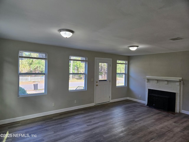 unfurnished living room featuring dark wood-type flooring and a brick fireplace