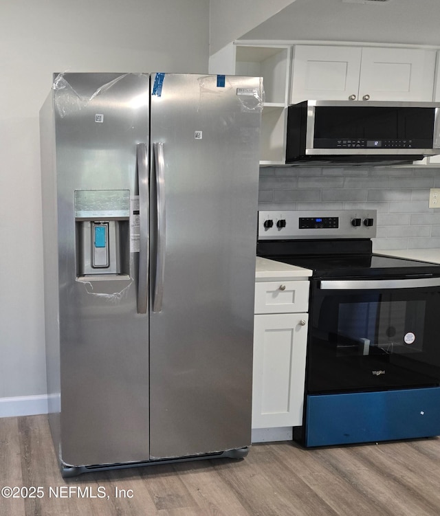 kitchen featuring tasteful backsplash, white cabinets, light hardwood / wood-style floors, and appliances with stainless steel finishes