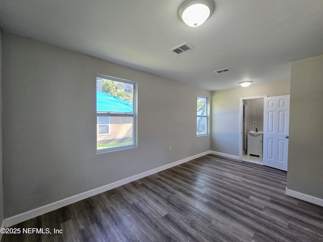 spare room featuring dark hardwood / wood-style flooring and a wealth of natural light