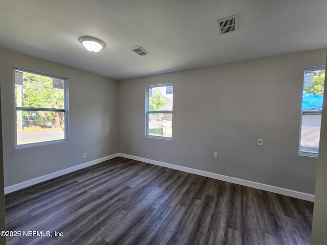 unfurnished room featuring plenty of natural light and dark wood-type flooring