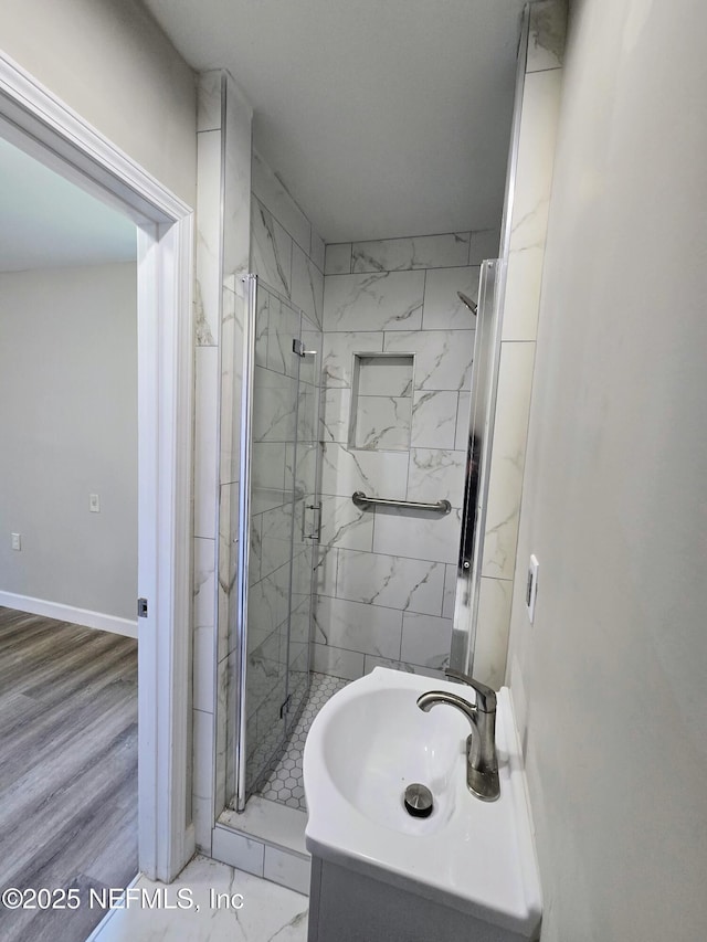 bathroom featuring sink, a shower with shower door, and wood-type flooring