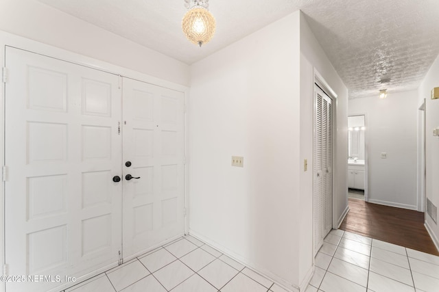 entryway with light tile patterned floors and a textured ceiling