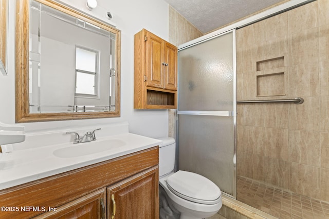 bathroom featuring walk in shower, vanity, toilet, and a textured ceiling