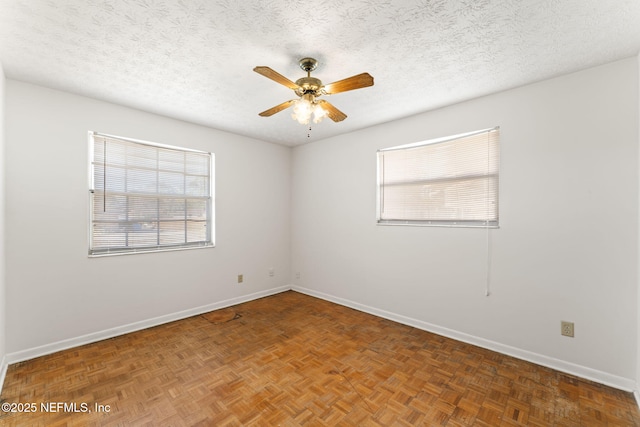 empty room featuring ceiling fan, dark parquet flooring, and a textured ceiling