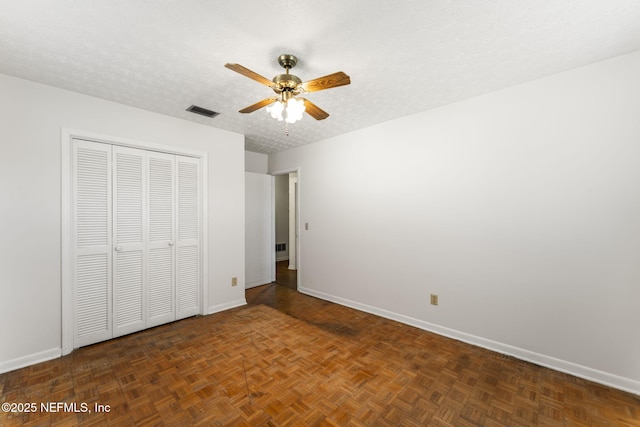 unfurnished bedroom featuring a textured ceiling, dark parquet floors, a closet, and ceiling fan