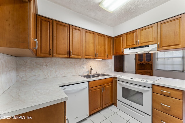 kitchen with sink, light tile patterned floors, white appliances, kitchen peninsula, and a textured ceiling