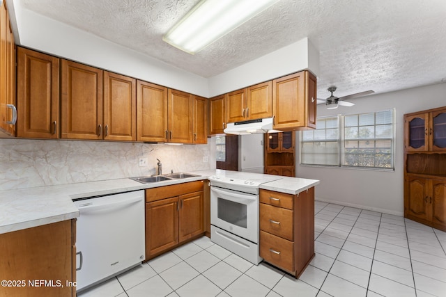 kitchen with white appliances, kitchen peninsula, sink, and a textured ceiling