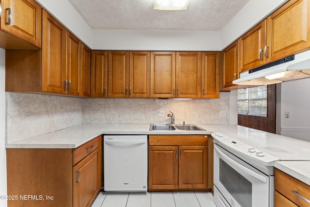 kitchen featuring sink, decorative backsplash, light tile patterned floors, white appliances, and a textured ceiling