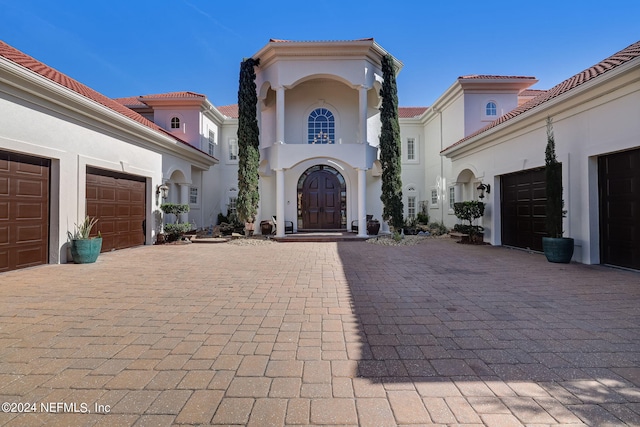 mediterranean / spanish home featuring decorative driveway, a tile roof, and stucco siding