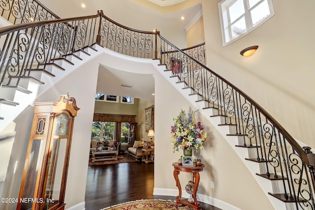 stairway with hardwood / wood-style floors and a towering ceiling