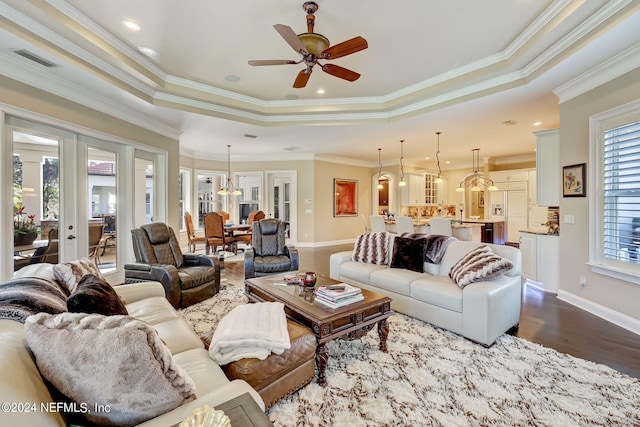 living room featuring ornamental molding, a tray ceiling, visible vents, and wood finished floors