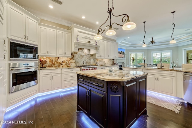 kitchen with appliances with stainless steel finishes, white cabinets, light stone counters, and pendant lighting