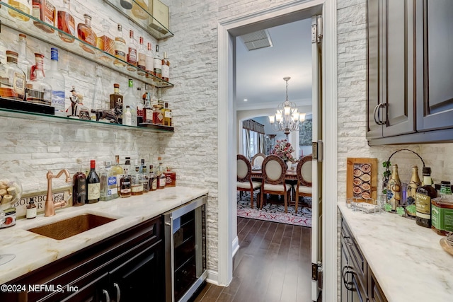 bar featuring wine cooler, dark wood-style flooring, a sink, a bar, and crown molding