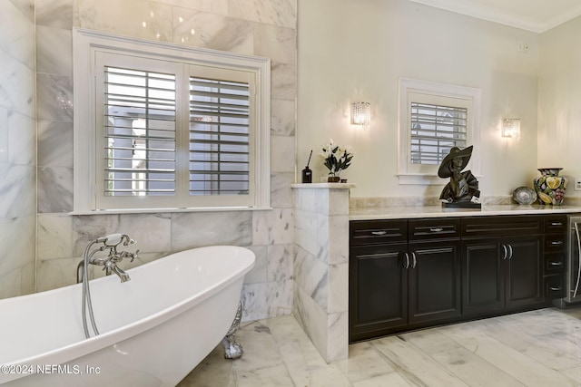 full bath with tile walls, ornamental molding, vanity, a freestanding tub, and plenty of natural light