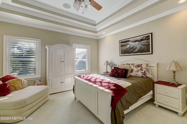 bedroom with light carpet, ceiling fan, a tray ceiling, and ornamental molding