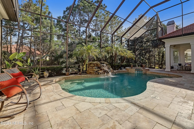 view of swimming pool with a patio area, glass enclosure, and a pool with connected hot tub