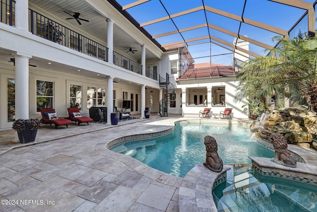 view of pool with a lanai, ceiling fan, a pool with connected hot tub, and a patio