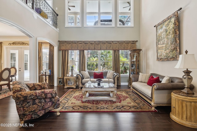 living area with dark wood-style floors, french doors, arched walkways, and a wealth of natural light