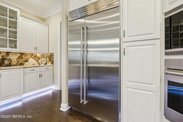 kitchen with dark wood-style flooring, crown molding, glass insert cabinets, white cabinetry, and built in appliances