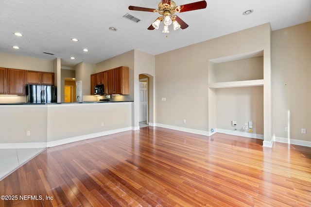 unfurnished living room featuring ceiling fan, a textured ceiling, and light hardwood / wood-style floors