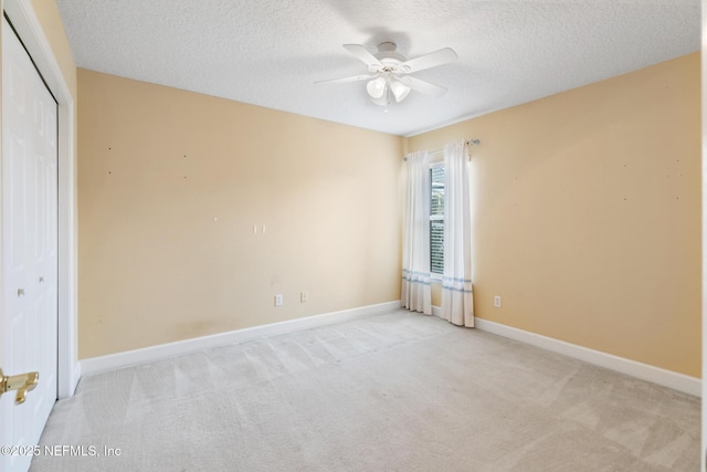 spare room with ceiling fan, light carpet, and a textured ceiling