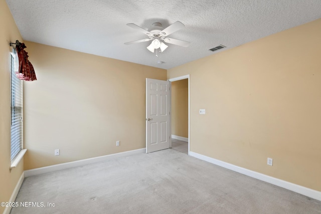 empty room featuring light carpet, ceiling fan, and a textured ceiling