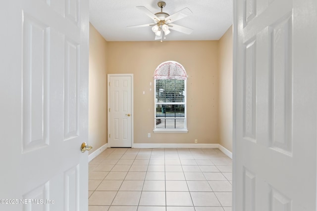 empty room with light tile patterned flooring, a textured ceiling, and ceiling fan