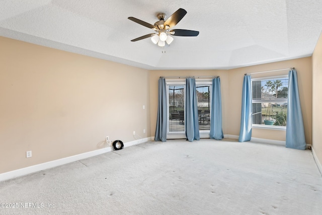 carpeted empty room with ceiling fan, a tray ceiling, and a textured ceiling