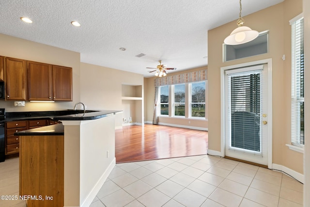 kitchen featuring kitchen peninsula, a textured ceiling, hanging light fixtures, and light tile patterned floors