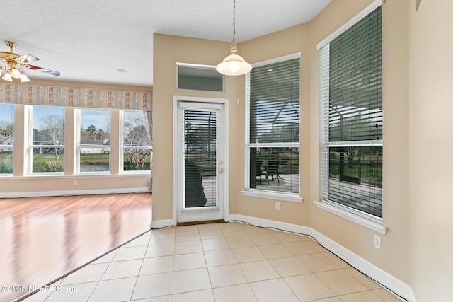 entryway with light tile patterned floors, a textured ceiling, and ceiling fan