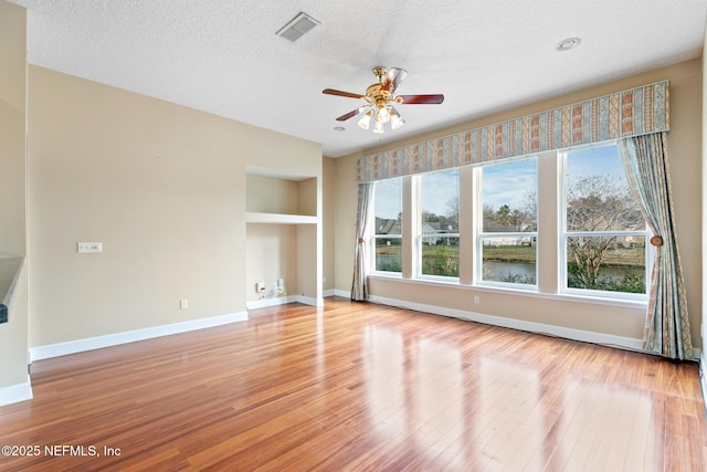 interior space with ceiling fan, built in features, light hardwood / wood-style flooring, and a textured ceiling