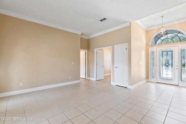 tiled foyer entrance with ornamental molding, a textured ceiling, and a notable chandelier