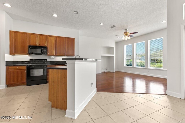 kitchen featuring light tile patterned floors, dark countertops, and black appliances