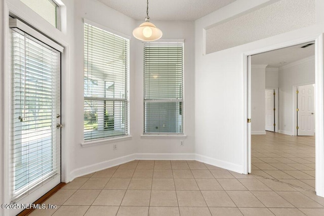 unfurnished dining area with light tile patterned floors, baseboards, a textured ceiling, and ornamental molding