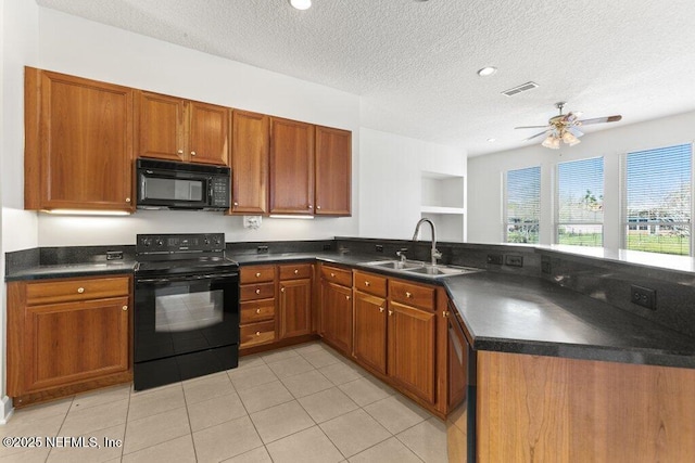 kitchen featuring visible vents, black appliances, a sink, dark countertops, and a peninsula