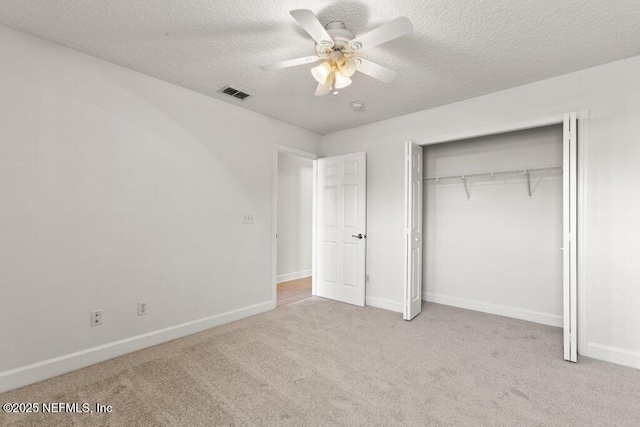 unfurnished bedroom featuring visible vents, baseboards, carpet floors, a closet, and a textured ceiling