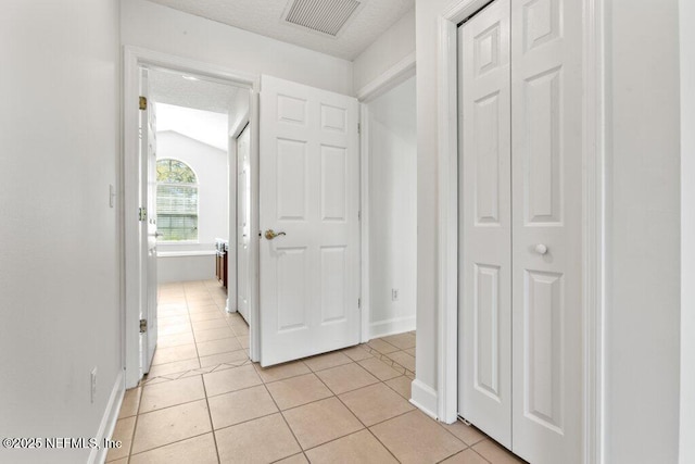 corridor with visible vents, baseboards, and light tile patterned flooring